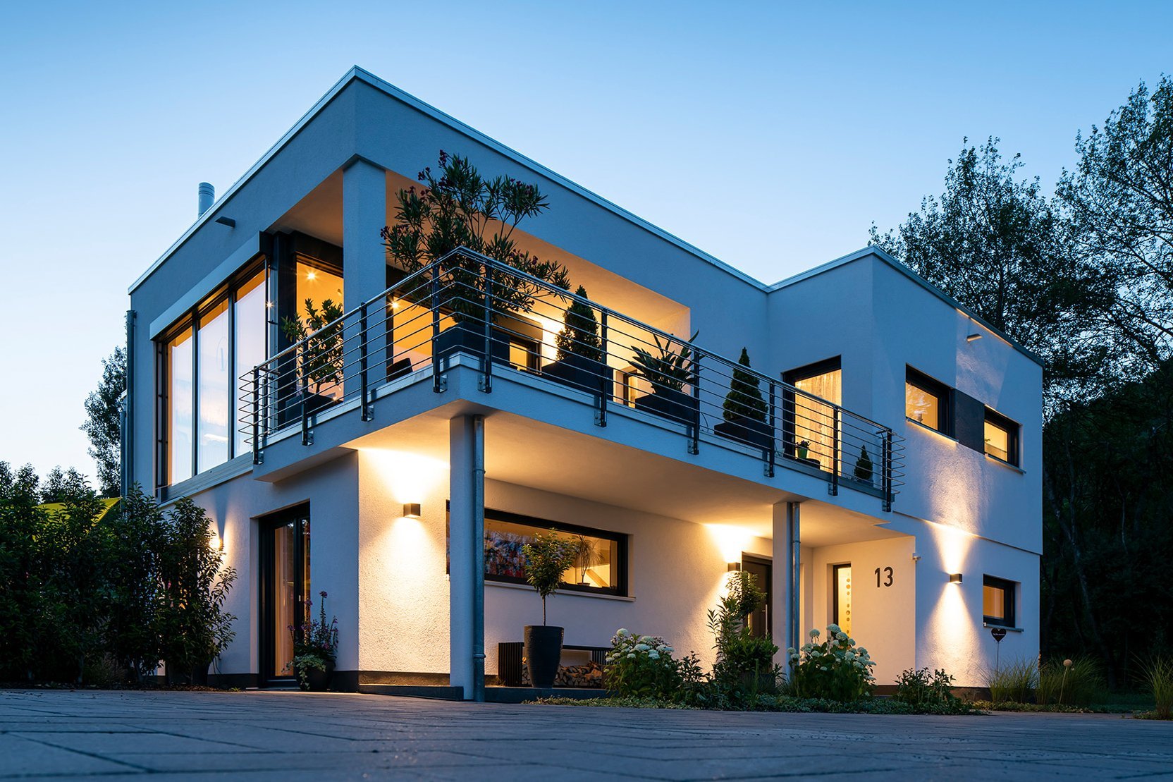 Flachdachvilla mit großzügigem Balkon und Fertigkeller von MB-Keller, modern beleuchtet in Abendstimmung